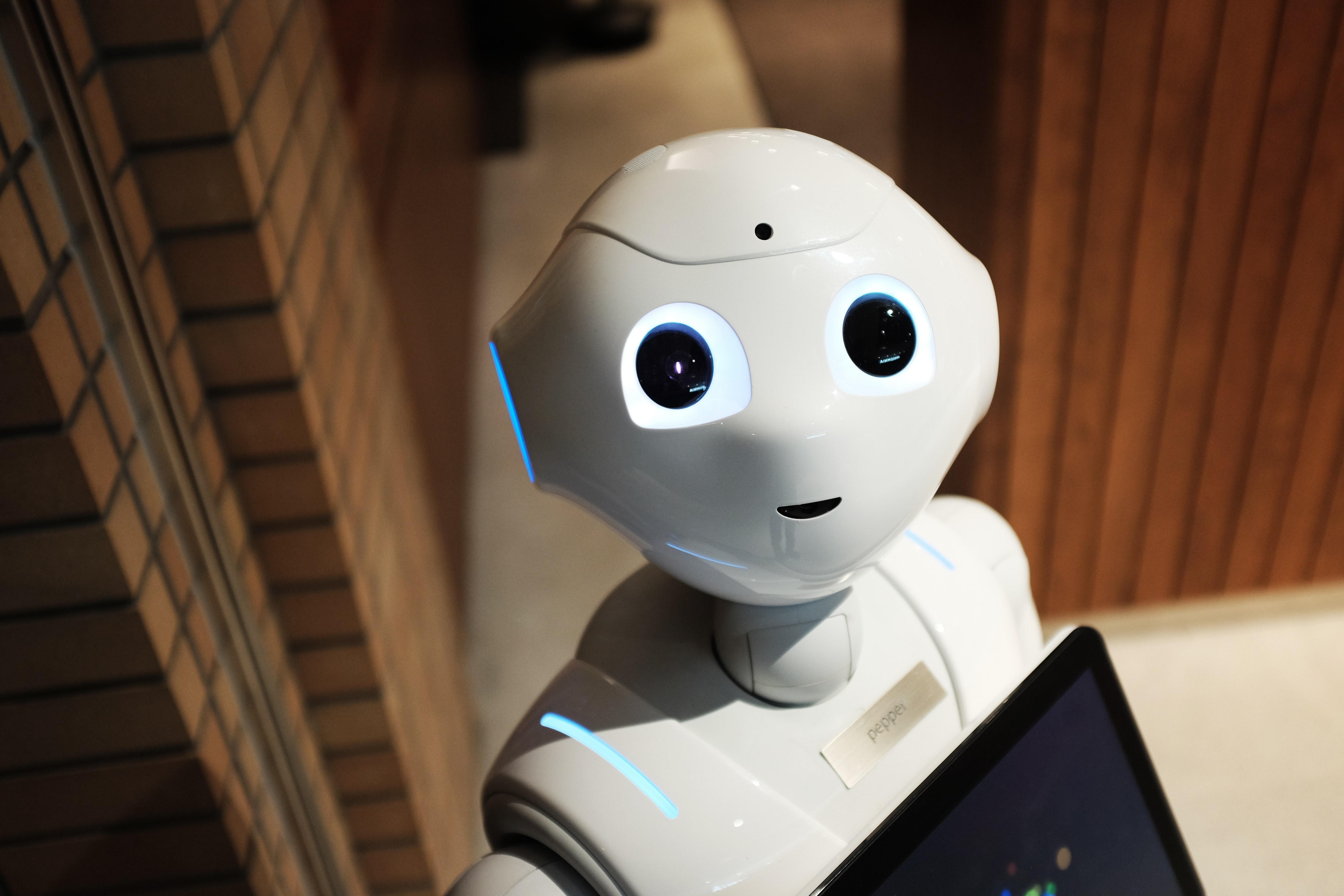 AI-robot med två svarta ögon och en liten mun i ett vitt, plastigt ansikte.